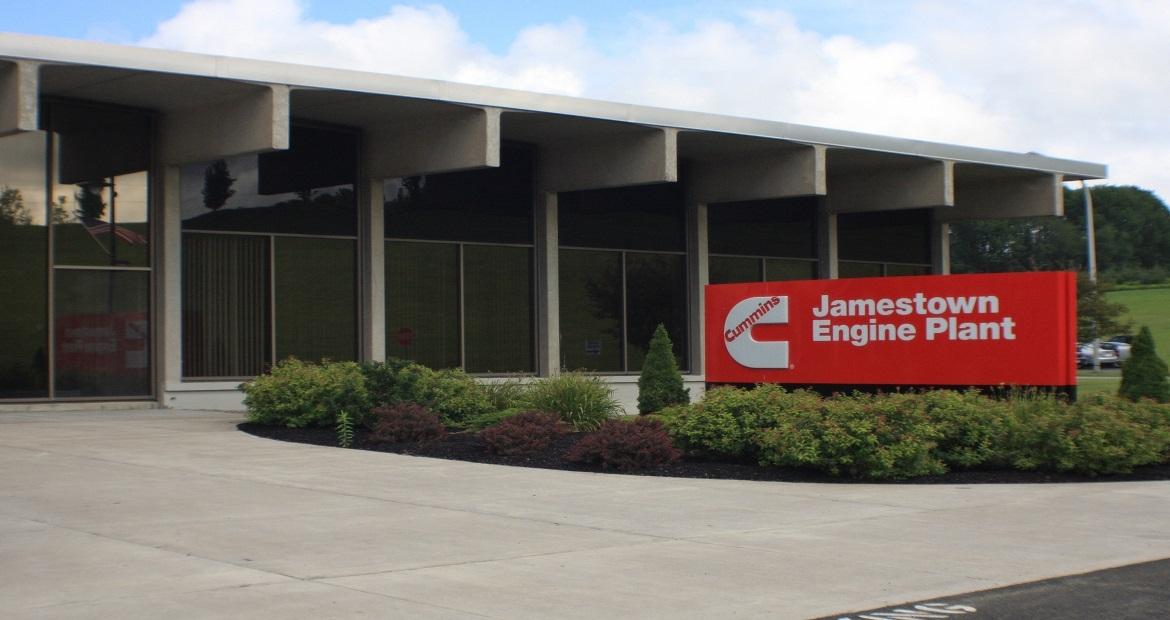 The front of a building with a red and white sign for Jamestown Engine Plant 