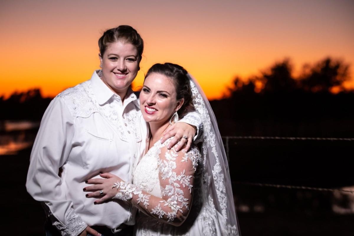 Kathryn and Emily in wedding attire, sunset behind them