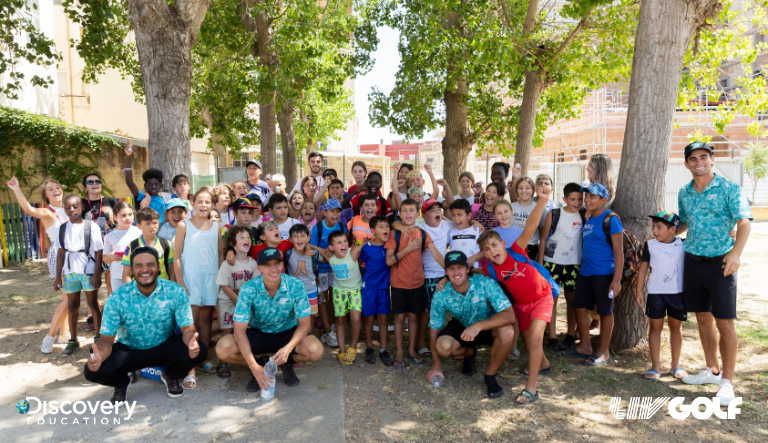 A large group photo of children and adults, taken outside underneath trees 