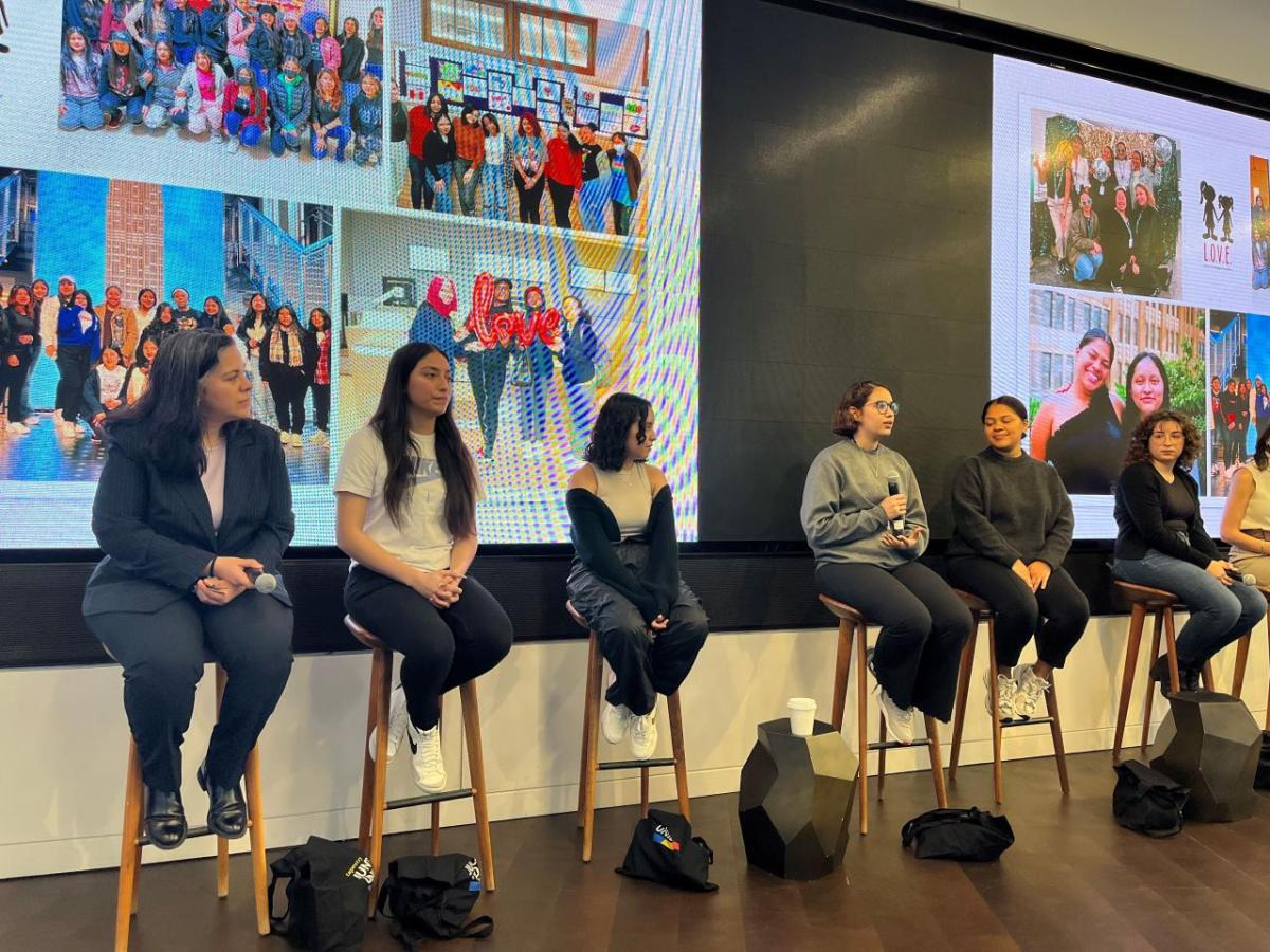 Six women sitting on stools engaged in a panel discussion