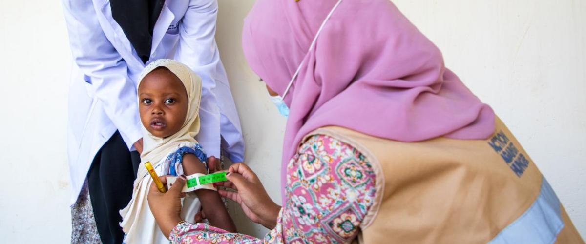 A health worker uses a mid- upper arm circumference (MUAC) band to detect malnutrition. / Photo by Abel Gichuru