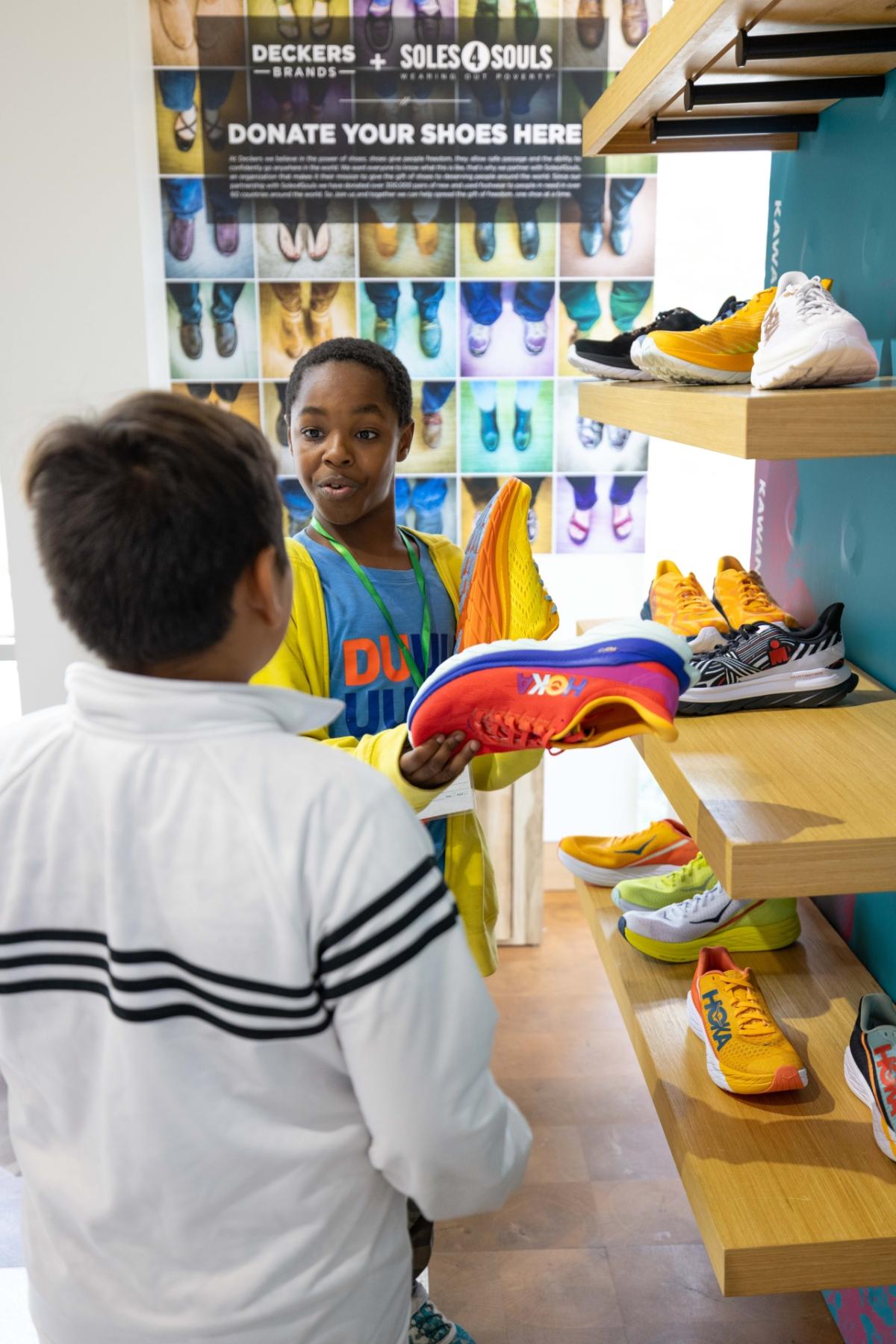 children holding Hoka shoes