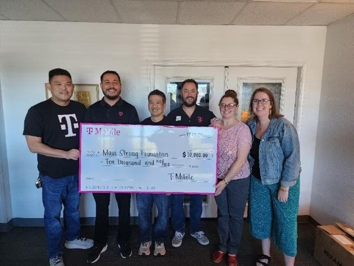 A group of people holding a donation cheque for Maui Strong Foundation