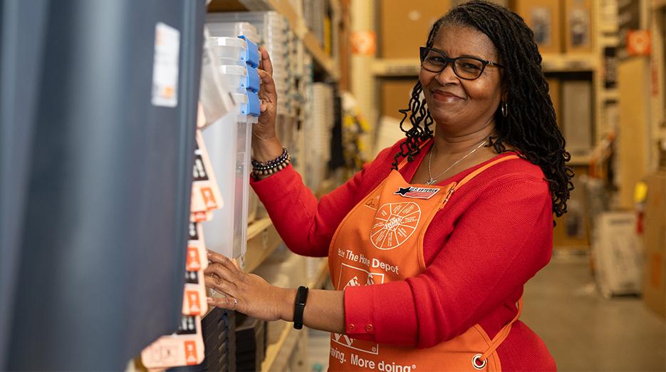 Home Depot associate shown in her store working on restocking a shelf.