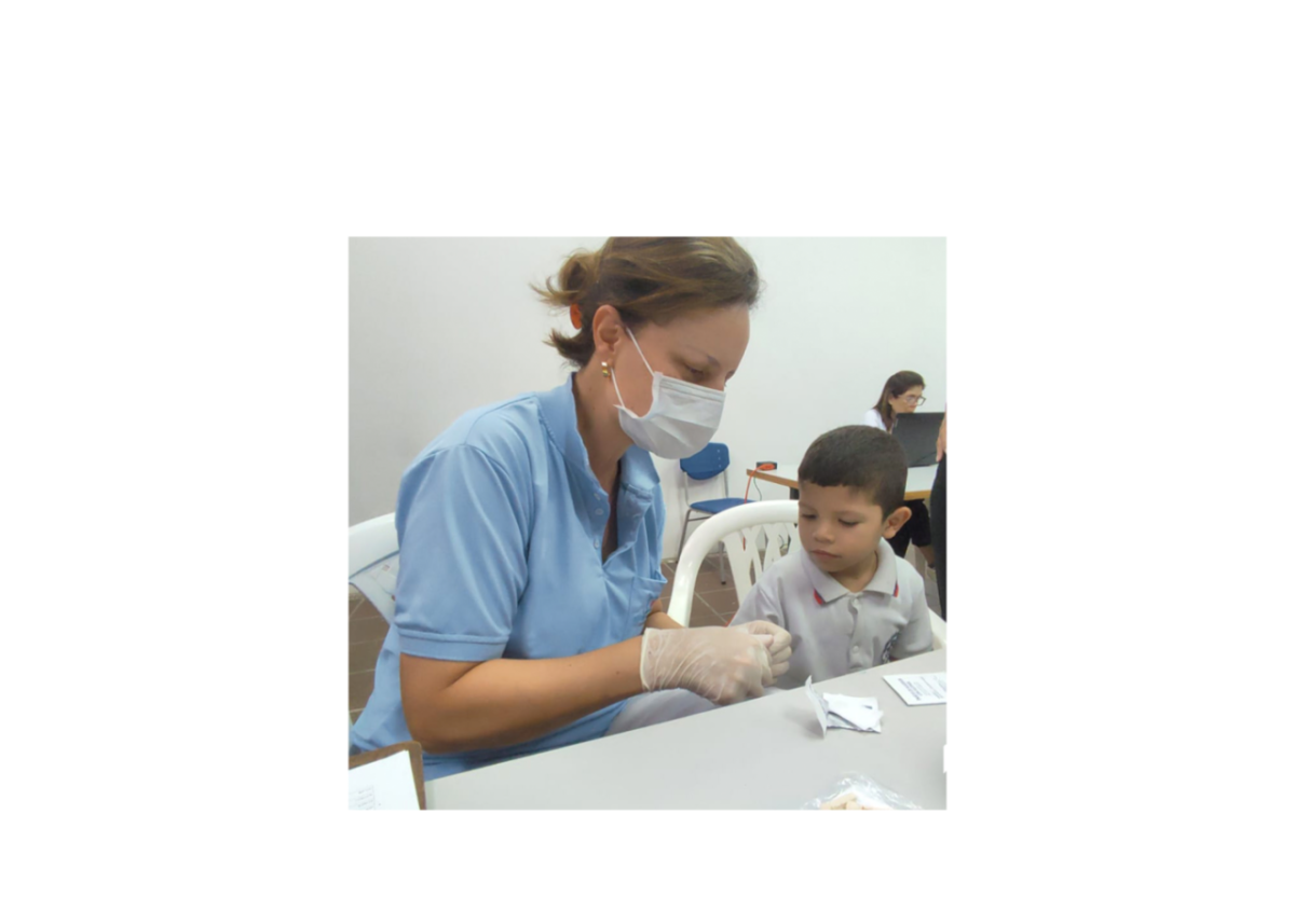 An adult in medical uniform giving a child a cup.