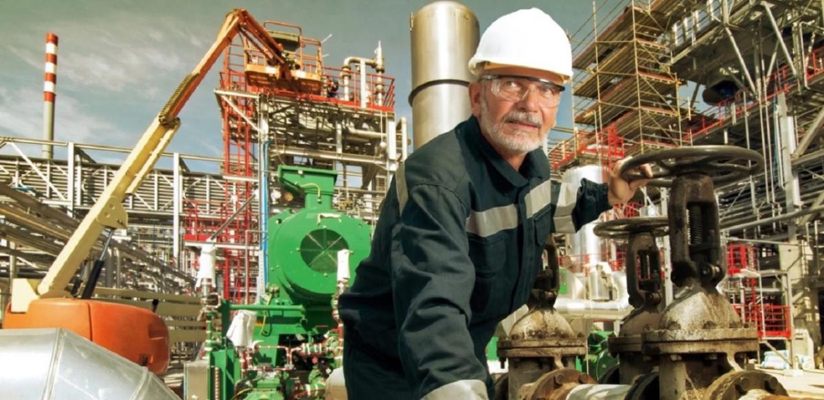 a worker in an industrial setting, cranes and scaffolding in the background