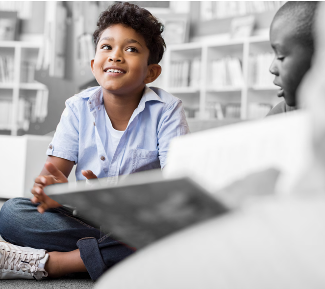 a student in color seated on the floor, everything else is in black and white. Book shelves behind them.