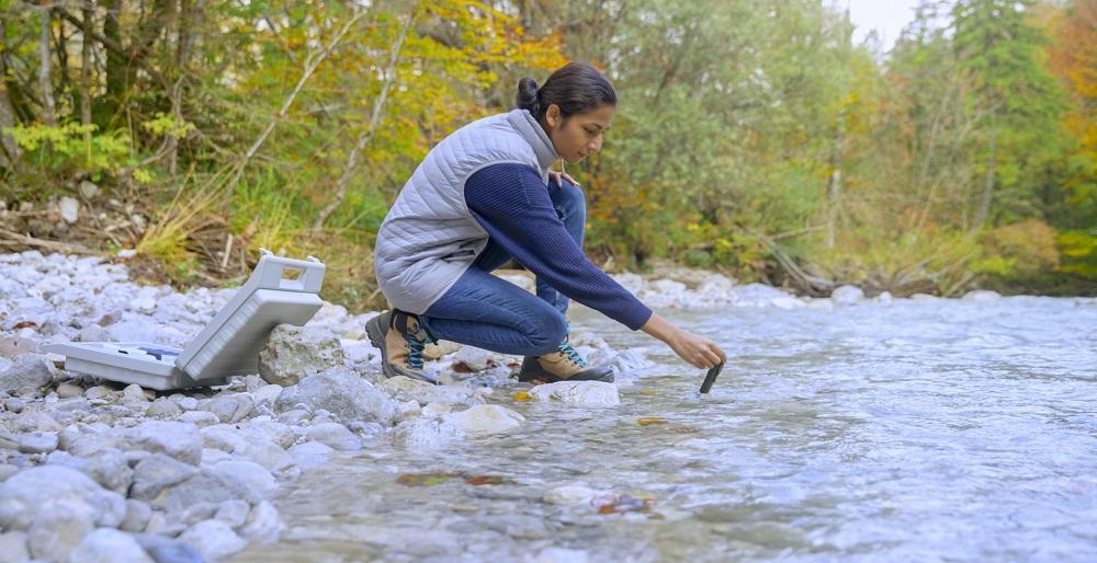 person collecting a water sample outside