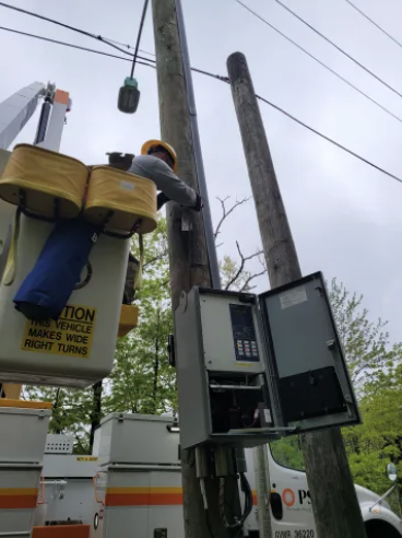 PSEG worker in cherry picker bucket working on electrical poles.