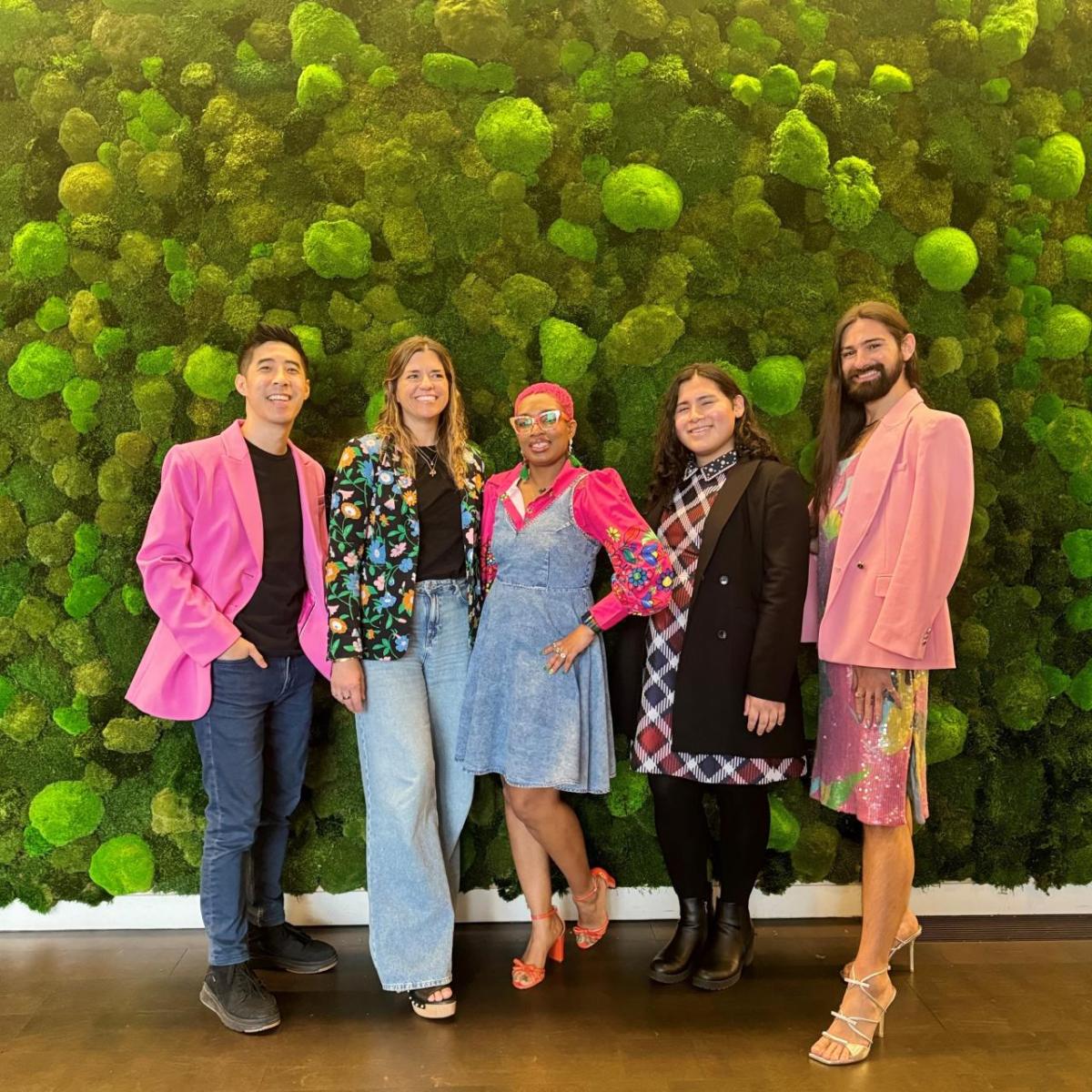 Panelists Salem Vazcones of the Hetrick-Martin Institute; Kevin Wong of the Trevor Project; Dr. Vivid (Dr. Ashley Elliott), a licensed clinician and youth advocate; and RJ Crossley, Prouder Together EBRG lead and Stuart Weitzman Store Manager standing in front of a moss-covered wall