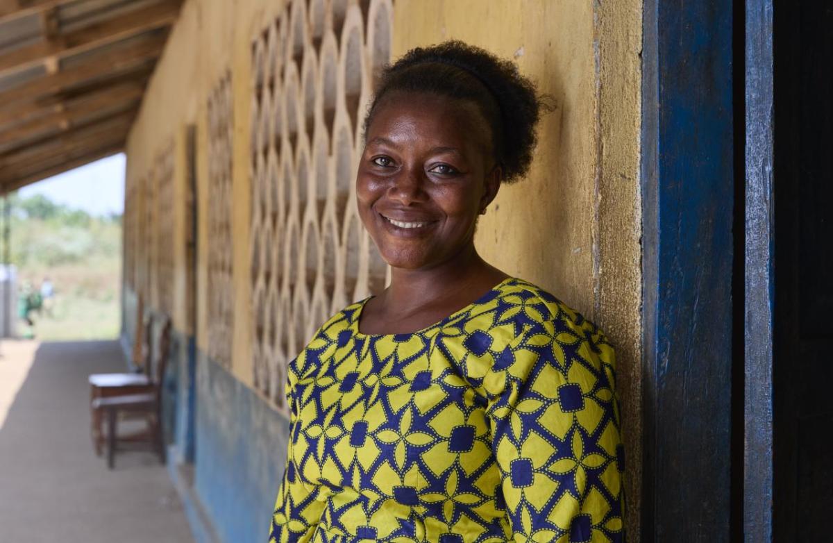 Portrait photo of Mabinty in front of the school she teaches at.