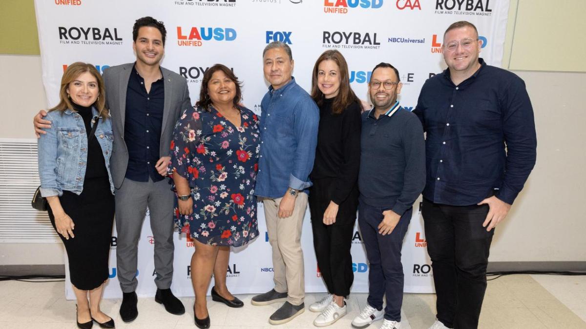 A team of seven posed in front of a screen with Roybal logos.