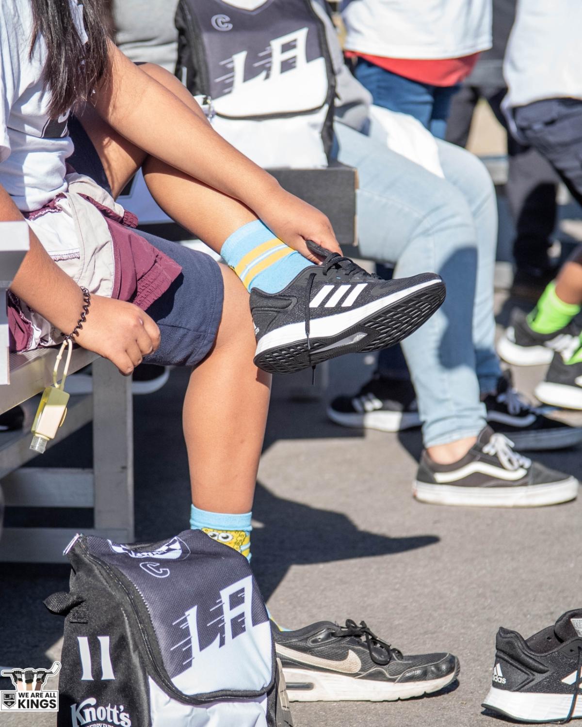 Students try on shoes on the playground during the Shoes That Fit event. 