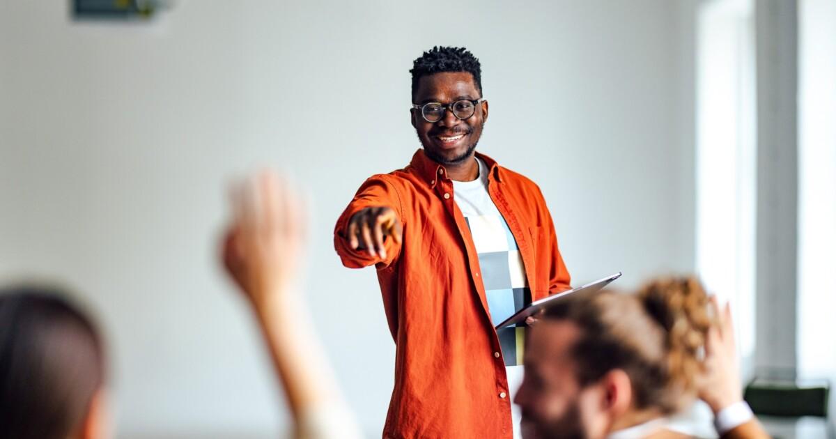 teacher in classroom calling on a student whose hand is raised