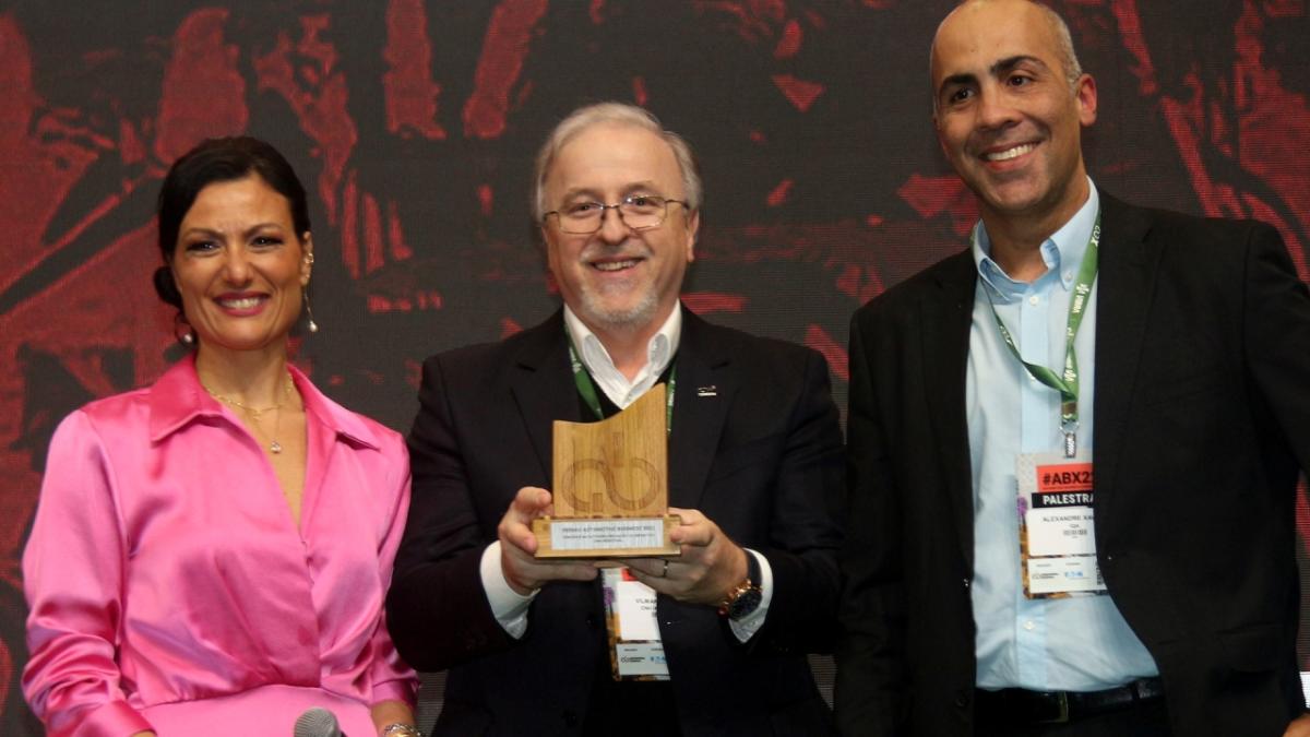 three people with the person in the center holding an award trophy