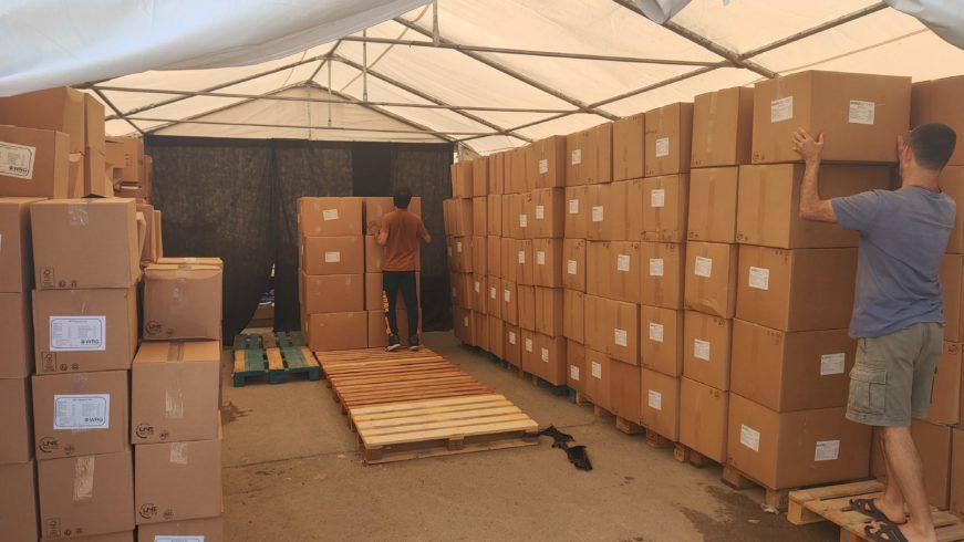 under a tent, many rows of stacked boxes