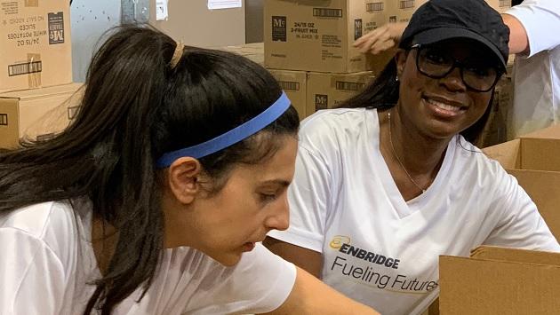 Volunteers packing boxes, wearing "Enbridge Fueling Futures" t-shirts.