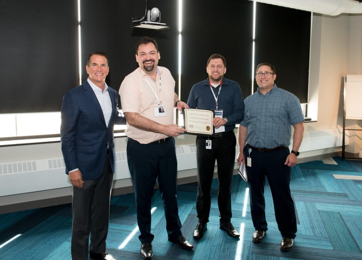 four people holding a certificate of achievement 