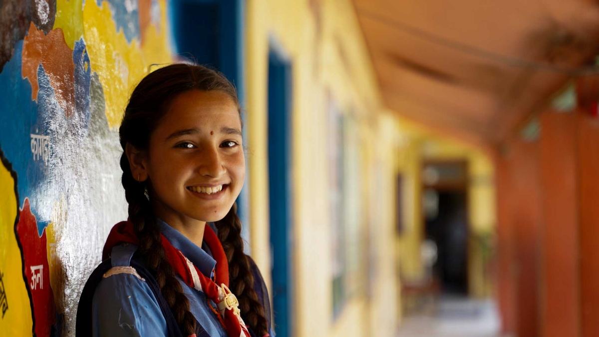 A smiling child standing in a hallway