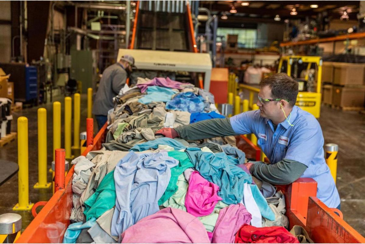 A person sorting through a line of waste apparel
