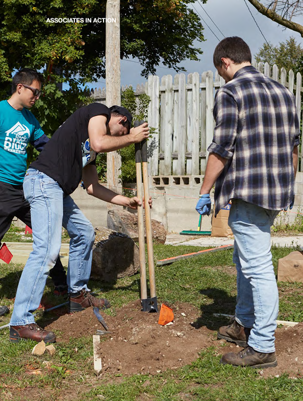 Three people using a post hole digger. "Associates in action"