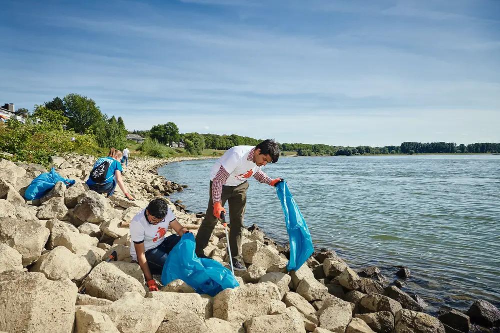 People collecting trash on a rocky beach.