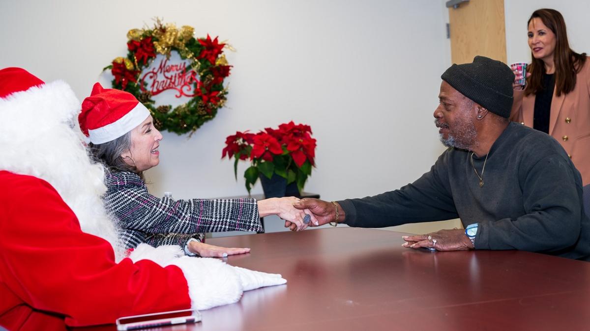 A recipient posed with Santa and Entergy employees.