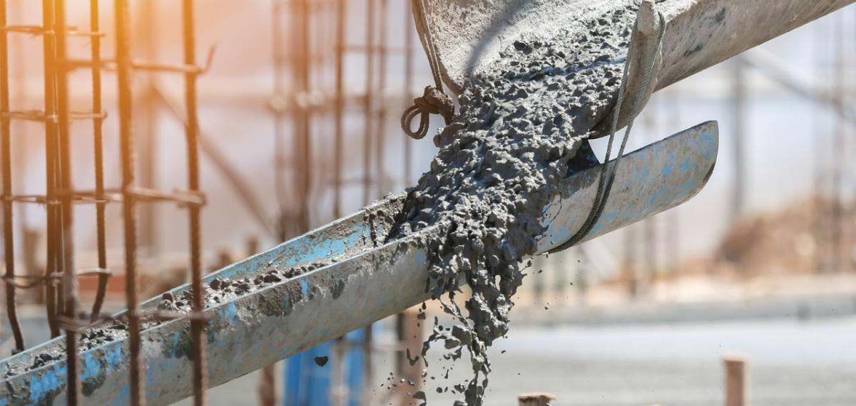 Concrete flowing down troughs at a construction site.