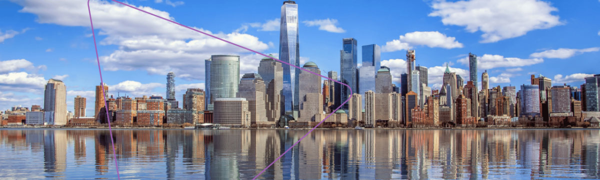 A city skyline, a body of water in front. A partly cloudy blue sky.