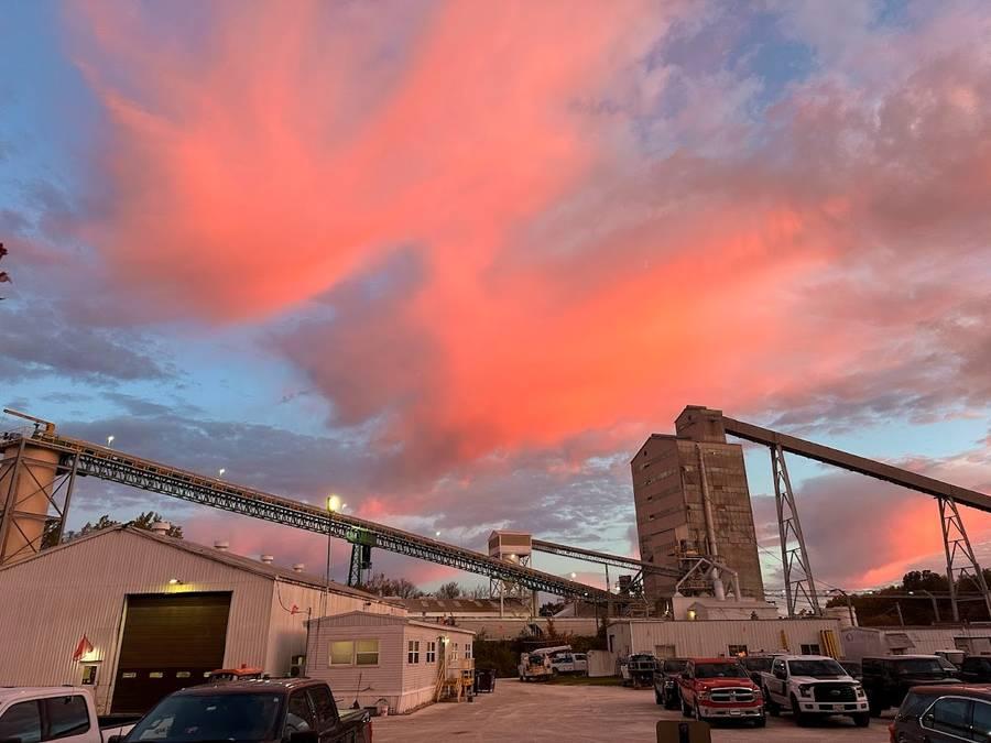 A sunset reflecting on clouds over an industrial setting.