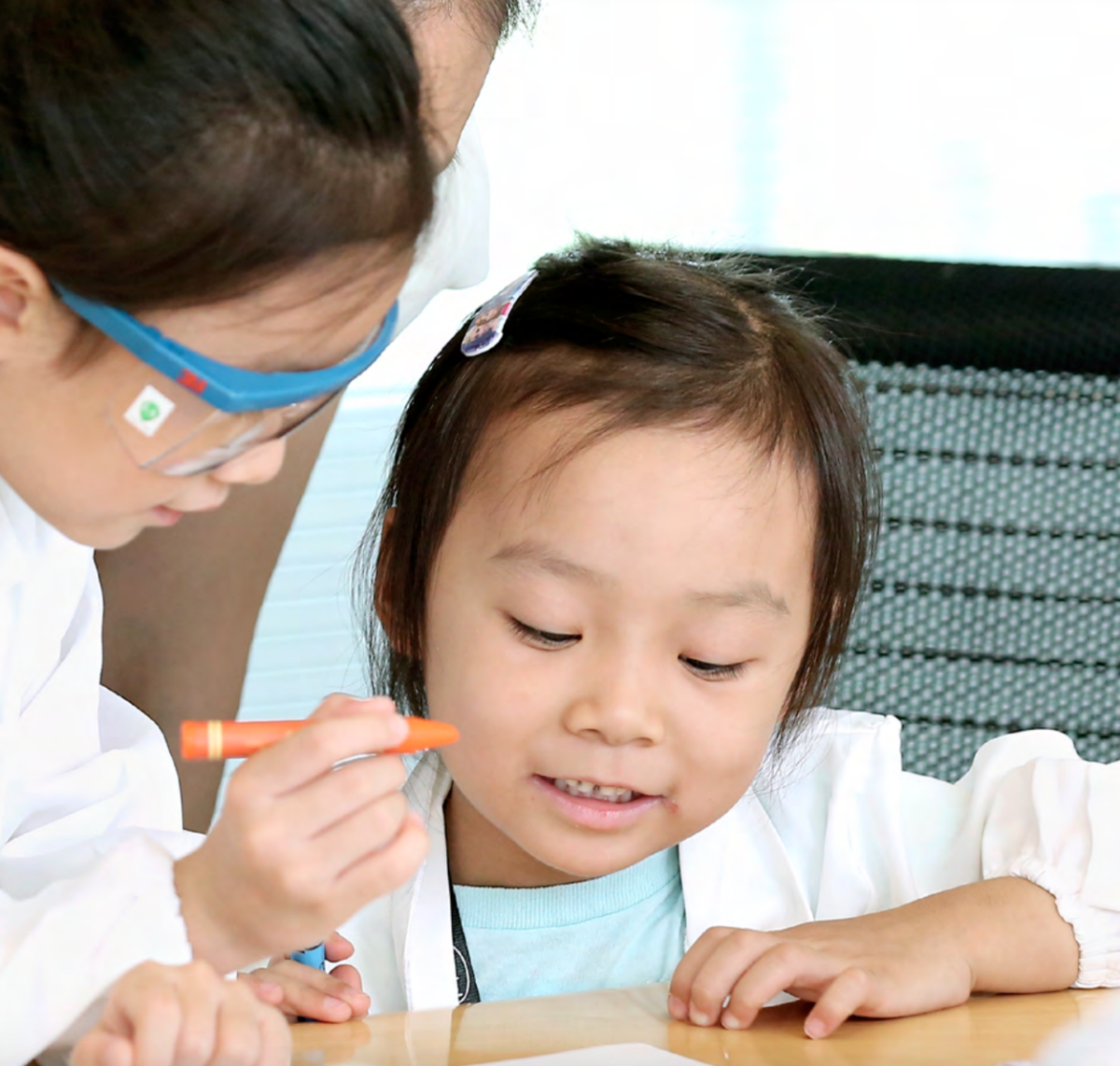 adult looking at a paper with a child holding a crayon