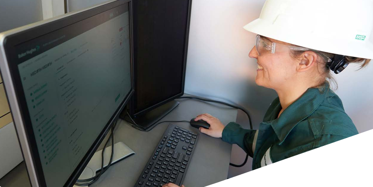 A person in protective gear working on a desktop computer.