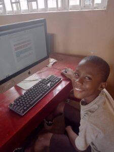 A smiling child using a computer.
