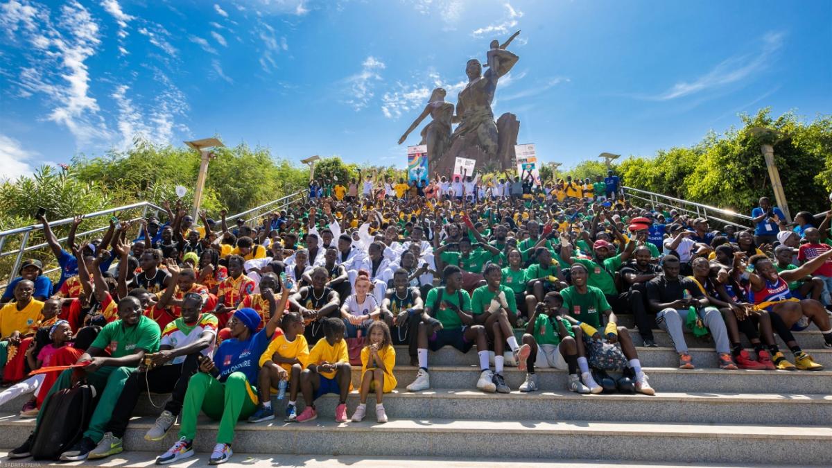 A large group of people outside, sitting on steps leading up to a monument