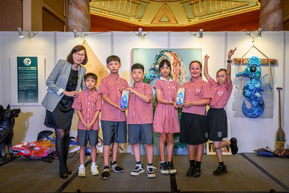 A group of children and an adult posed in front of an exhibit with sea creatures.