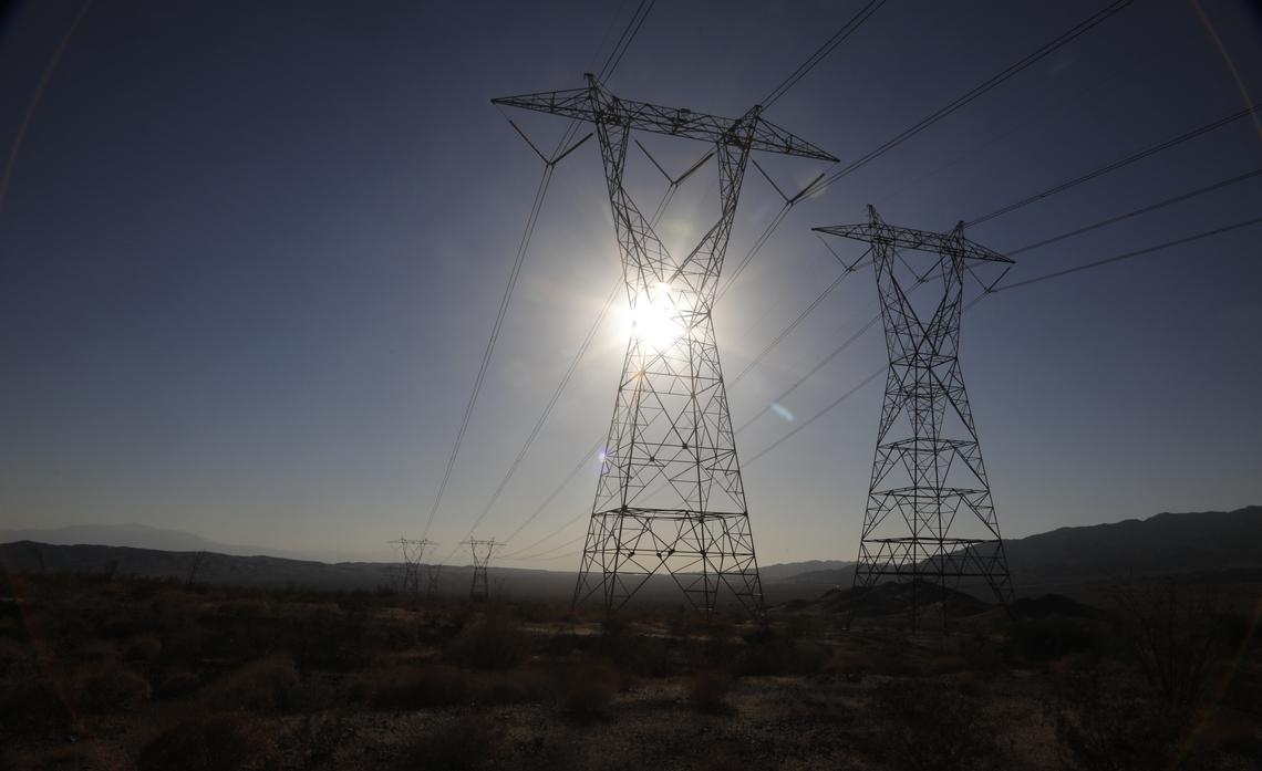 Tall power lines lined up with the sun over a large flat open landscape