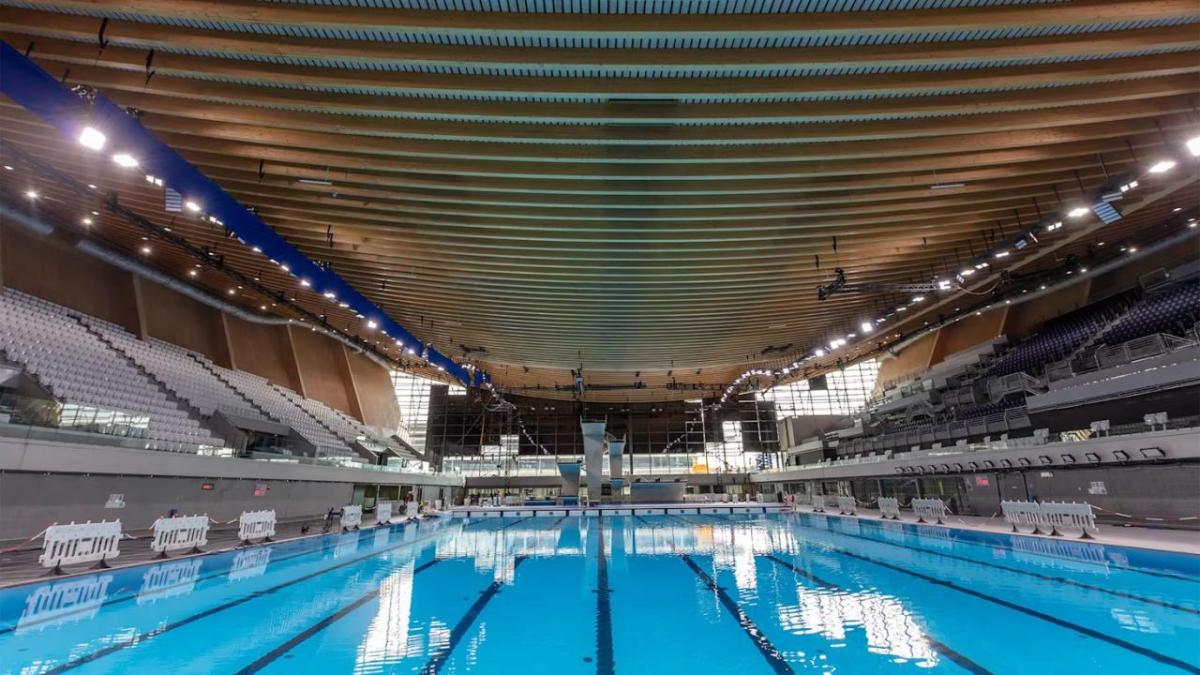 A large enclosed swimming pool with stadium seating on the sides