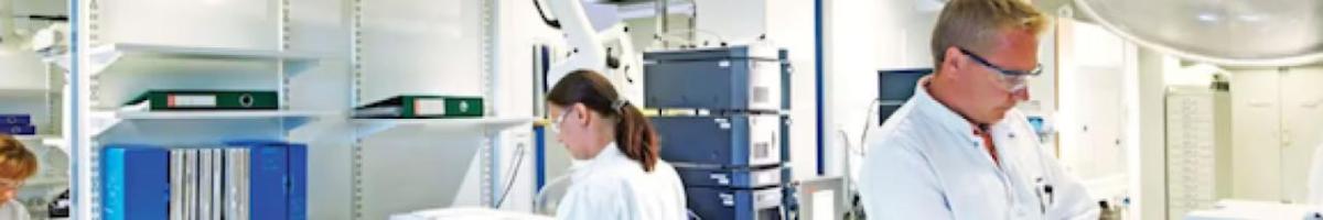 Two people in a lab wearing protective gear.