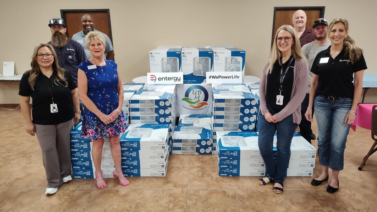 A group posed by stacks of fans in boxes.