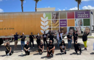 a large group of people in front of a "feeding America" semi trailer outside