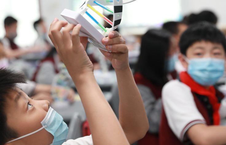 Masked child making paper DNA strand