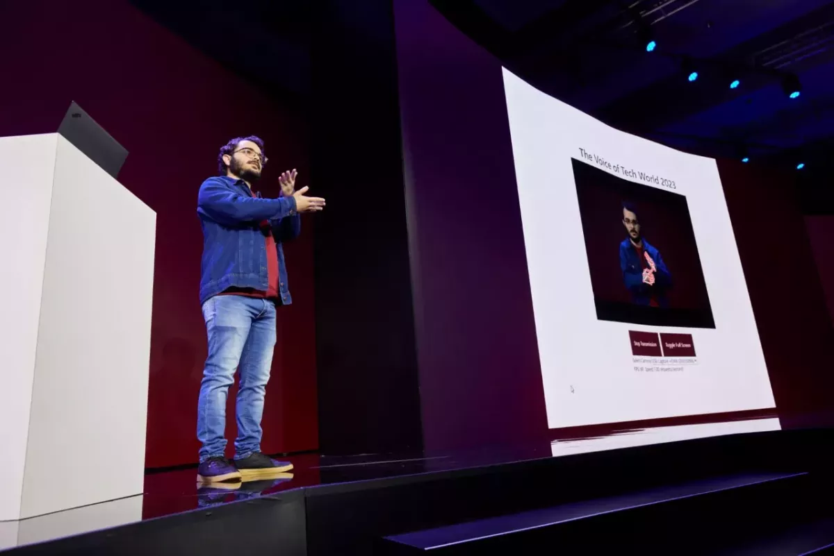 Gabriel presenting on stage using sign language and a digital display.