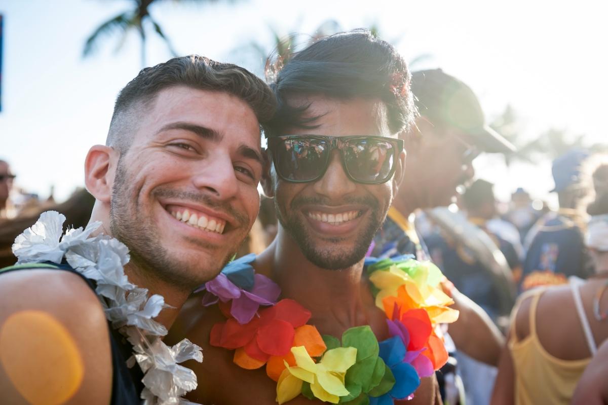 Two people wearing lai's in rainbow colors. Both are smiling.