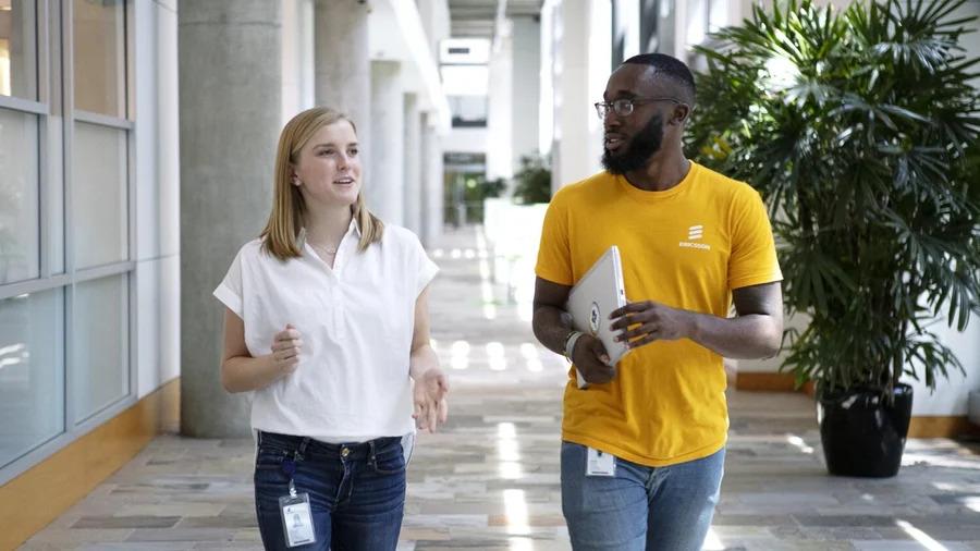 Two people walking and talking down a hallway.