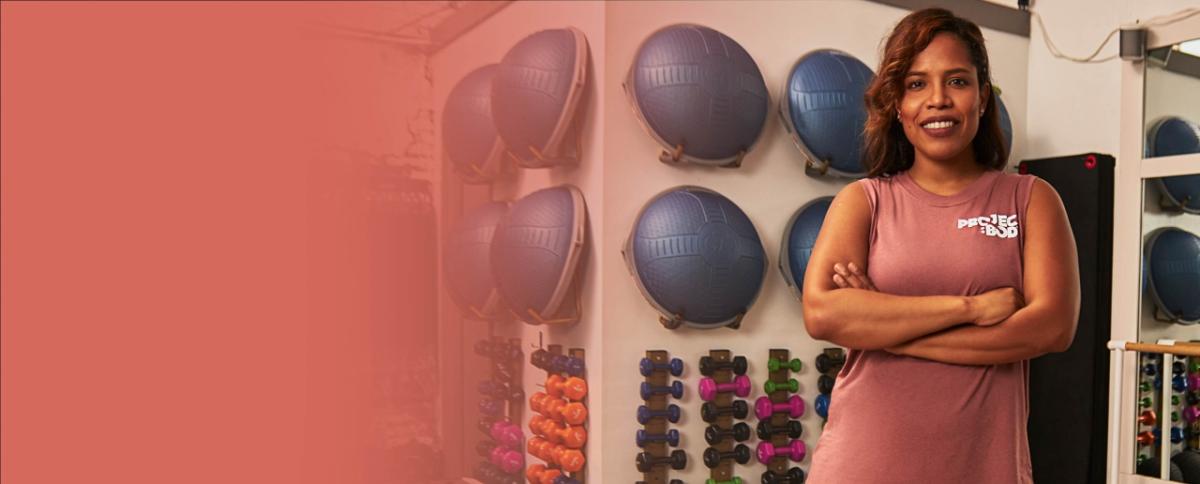 a person stands with arms crossed in front of a wall of exercise equipment