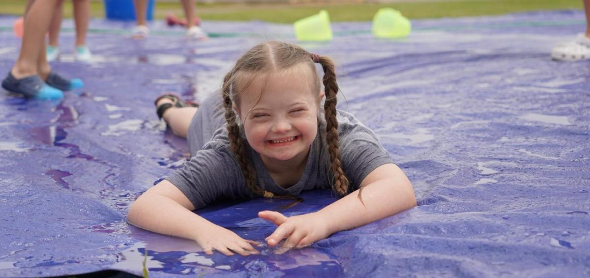 A child playing on a wet slide on the ground