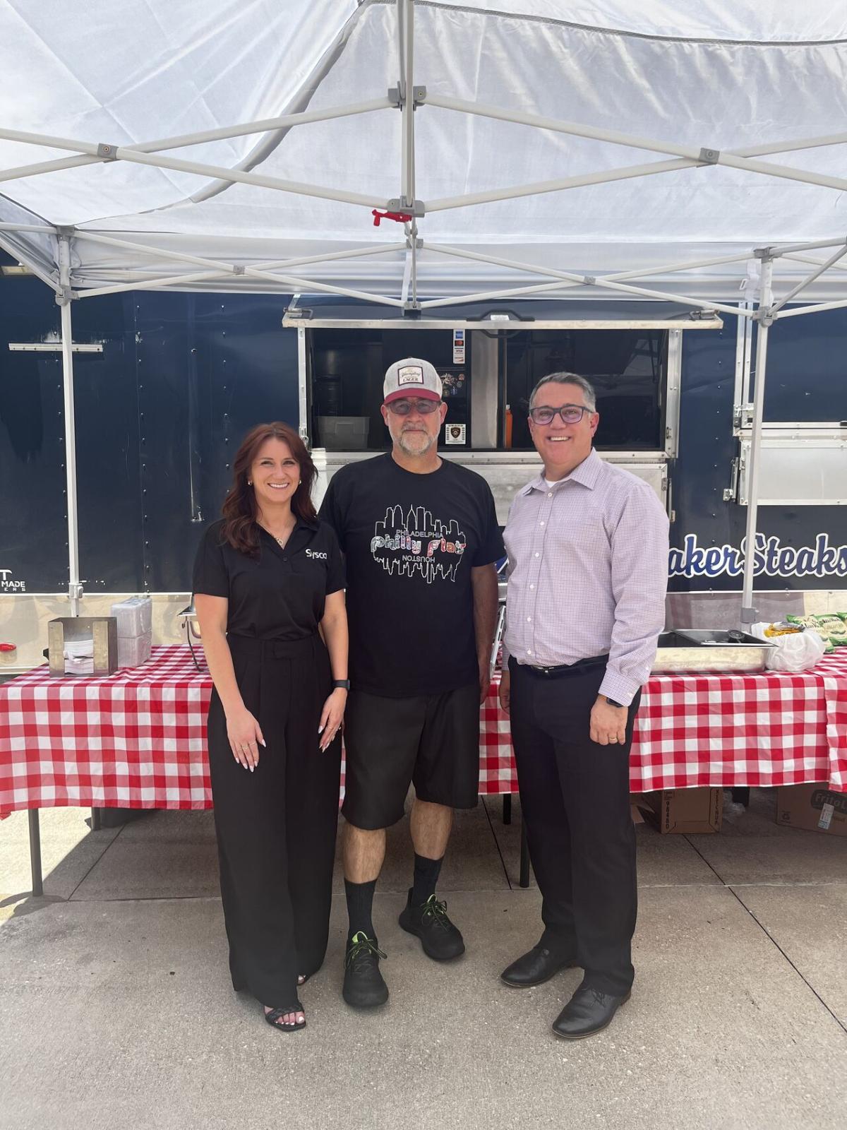 3 people standing together under food tent