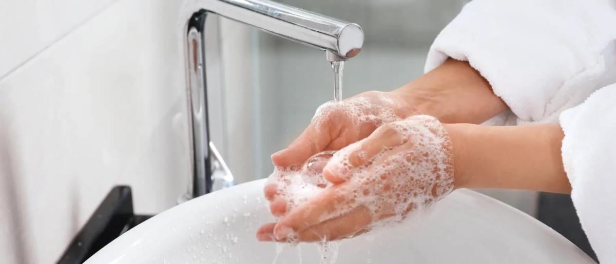 Close up of a person washing their hands in a sink.