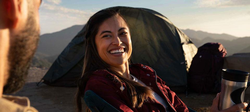 Person sat in front of a tent smiling 