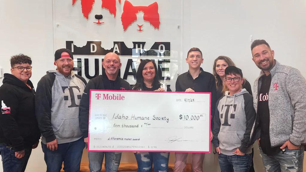 A small group posed with a large check in front of a sign "Idaho Humane"